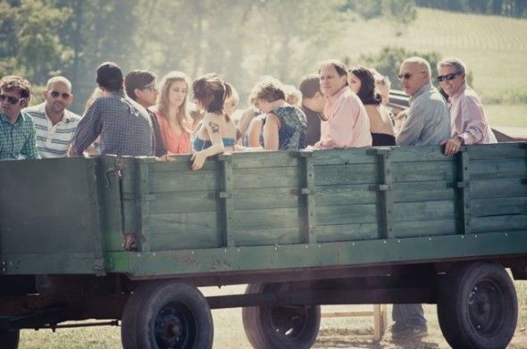 Guest arrive at wedding by a hay wagon