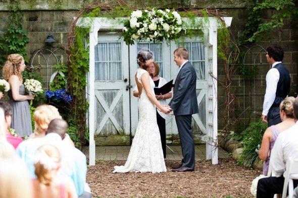 a rustic outdoor wedding ceremony under an arbor 
