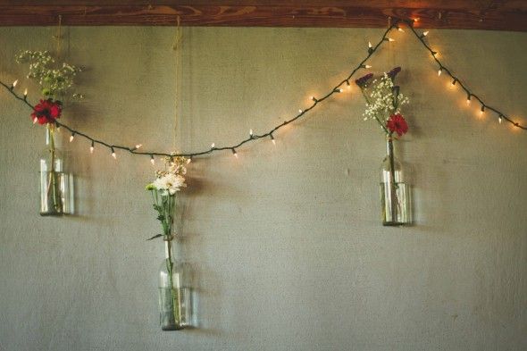 Vases of Flowers Hang in the Lights at a Country Wedding