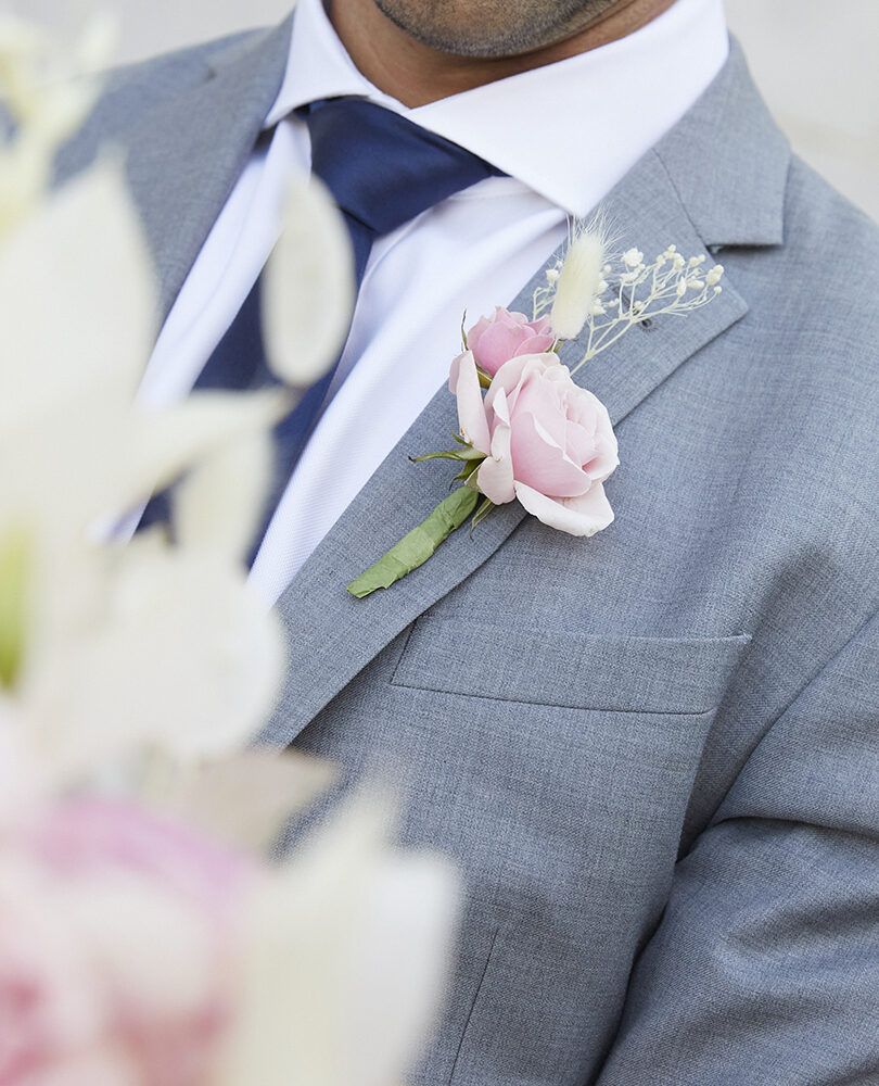 pink flower boutonniere on grey suit
