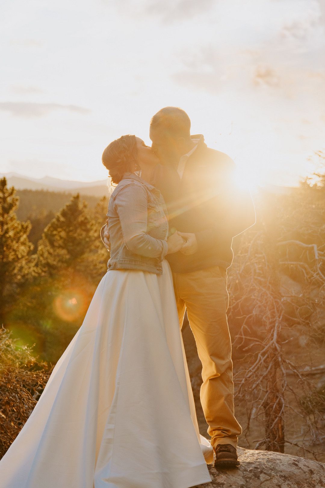 Bride and Groom kissing on mountains at sunset