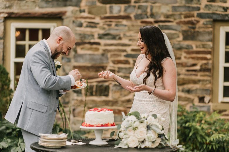 Bride putting wedding cake on grooms face and both laughing