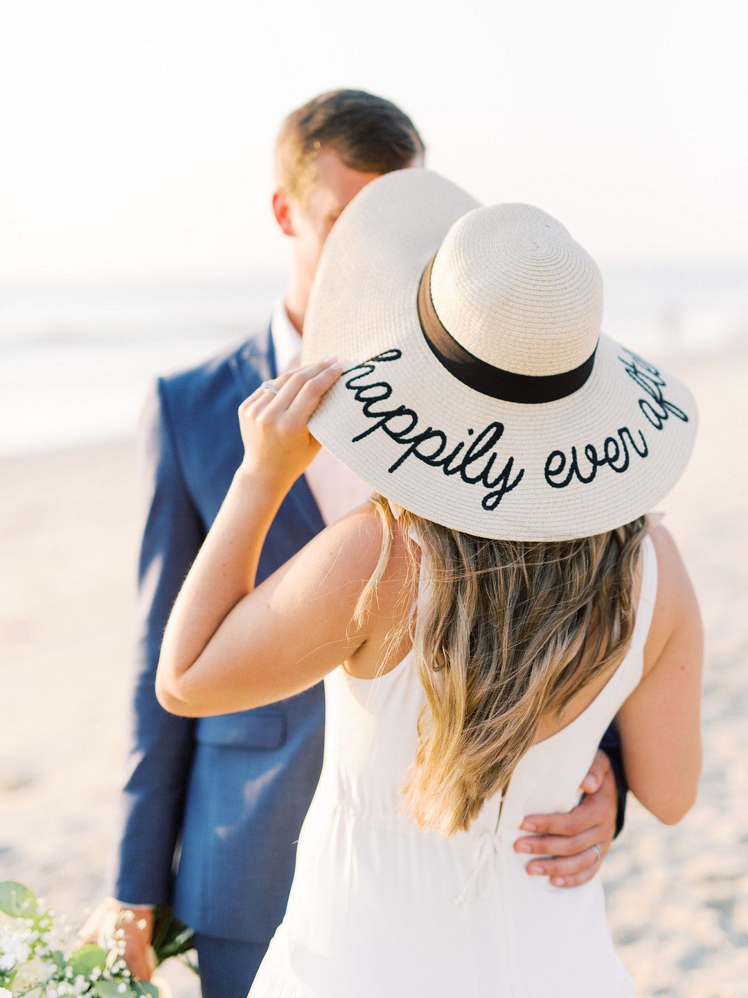 bride wearing a sun hat with the words "happily ever after"