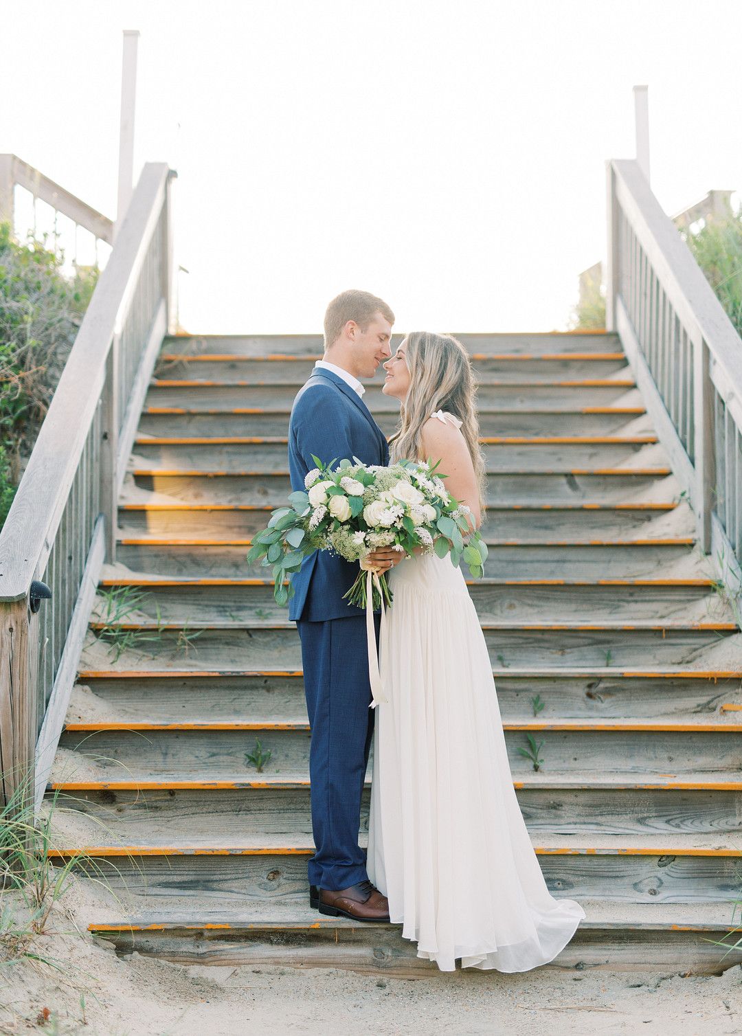 bride and groom standing together in front of a set of stairs