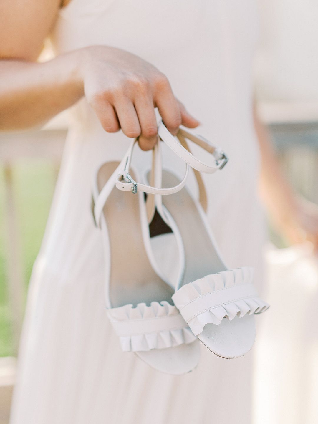 bride holding a pair of white sandals