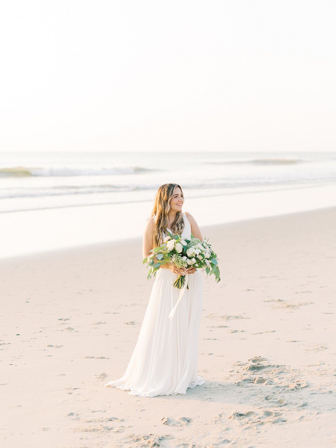 bride standing on the beach with her bouqet