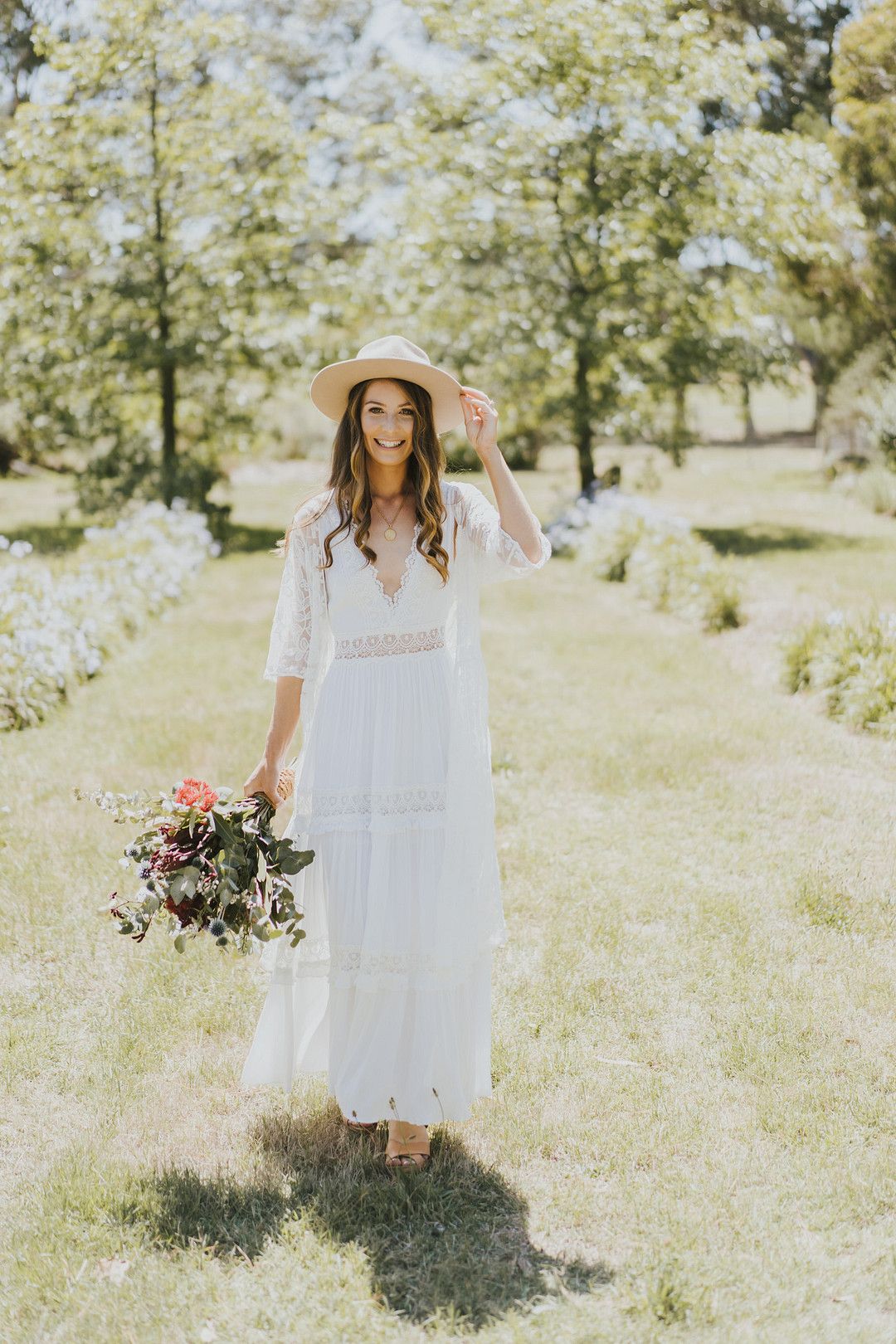 bride in white dress and hat in outdoor rustic wedding