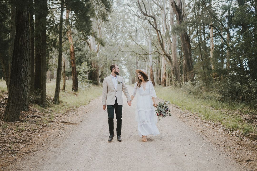 bride and groom holding hands for wooded wedding ceremony
