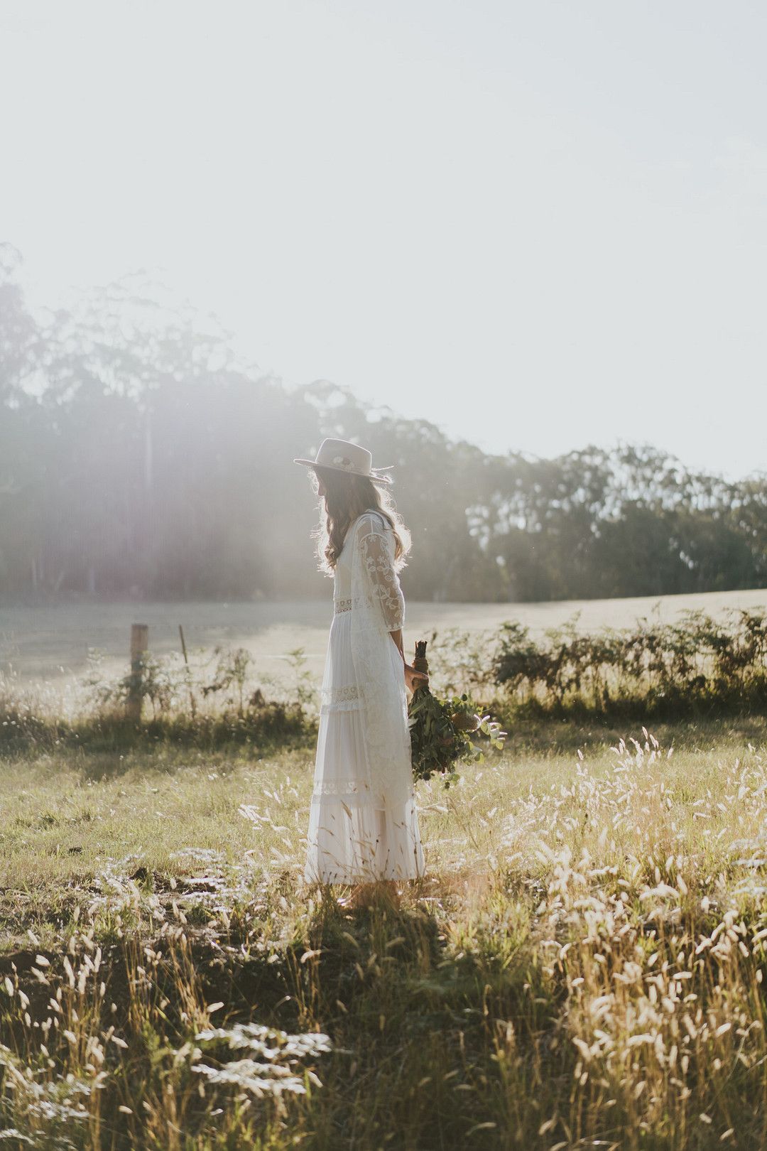 rustic bride in white wedding dress in field