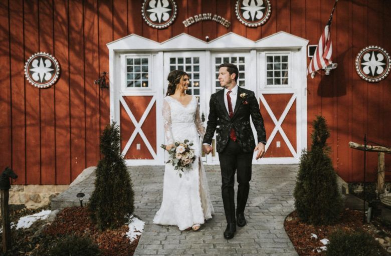Bride and Groom holding hands in front of barn
