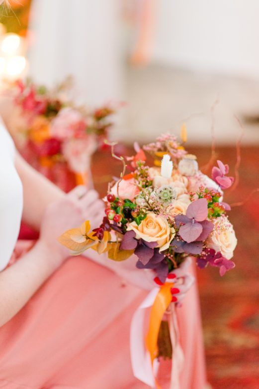Bridesmaid holding pink, purple, and orange bouquet