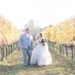 bride and groom walking through vineyard