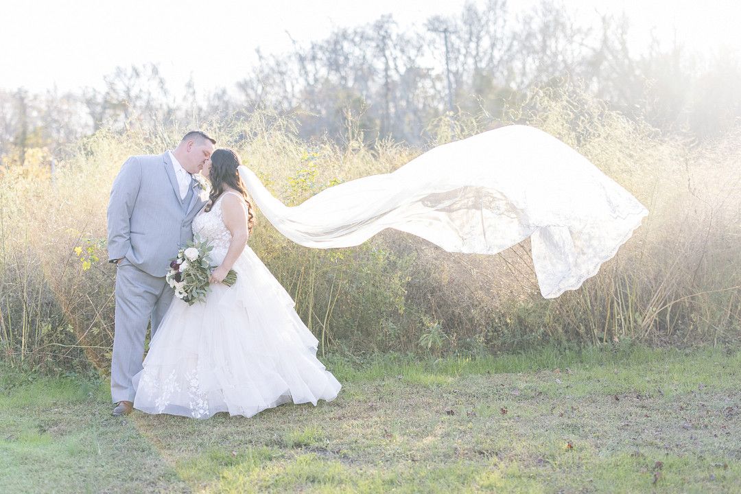 bride and groom kissing with the veil blowing in the wind