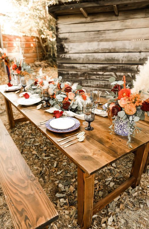 wooden table with orange toned florals and blue detailed dishes 