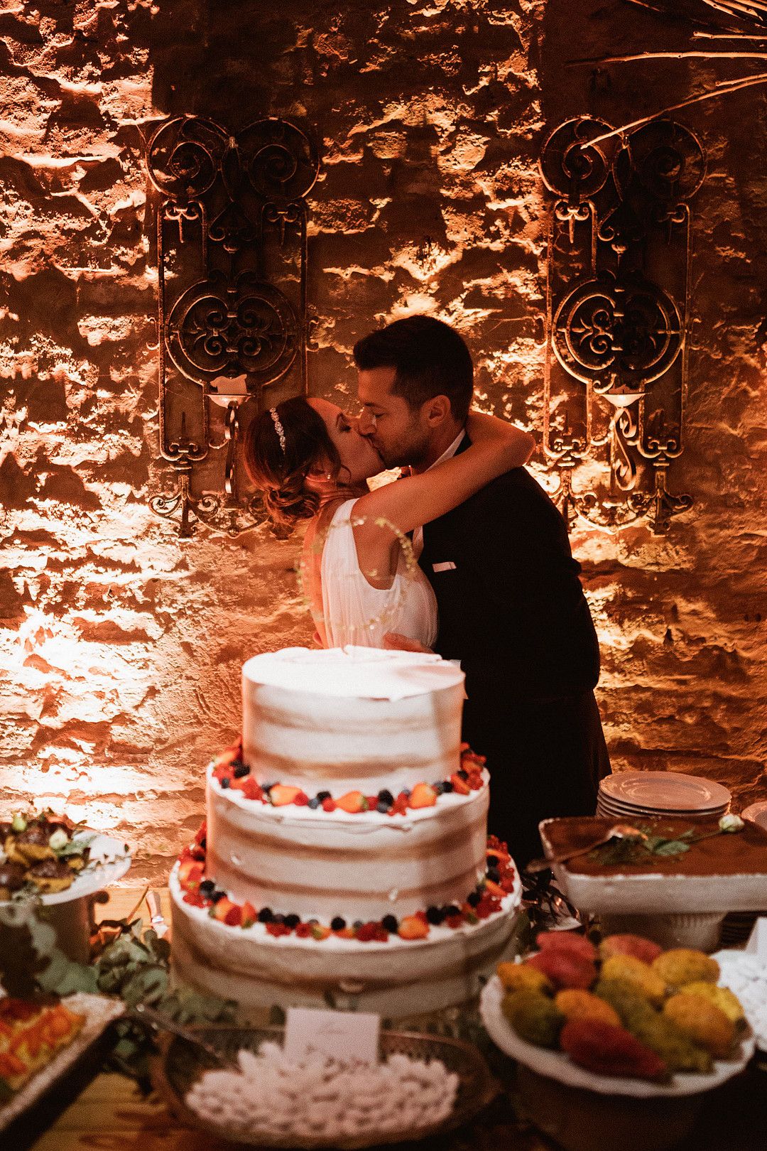 bride and groom kissing in front of cake