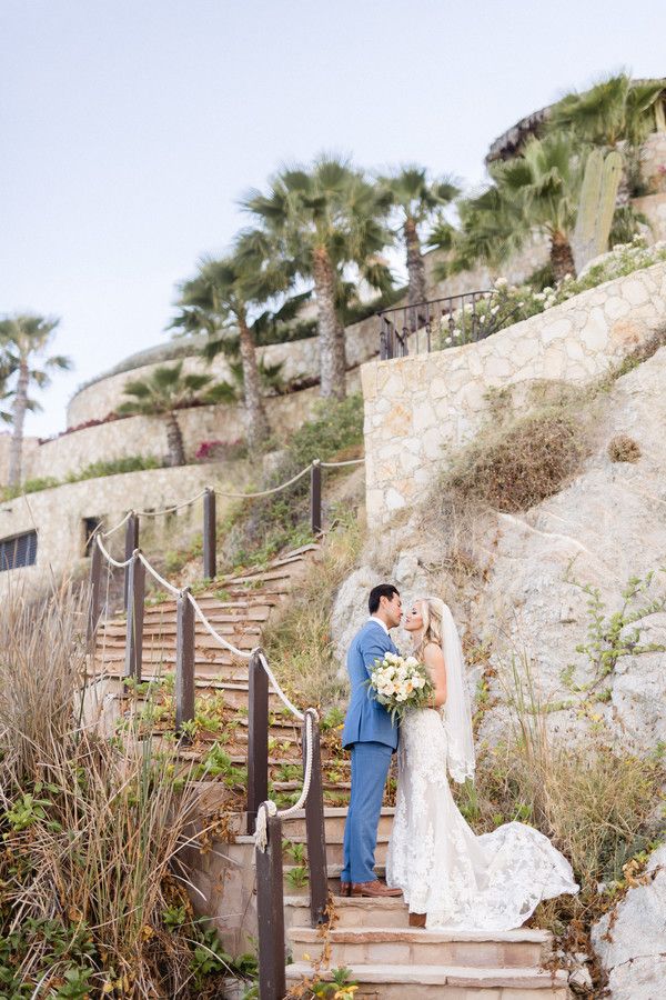 bride and groom kissing on steps of the beach