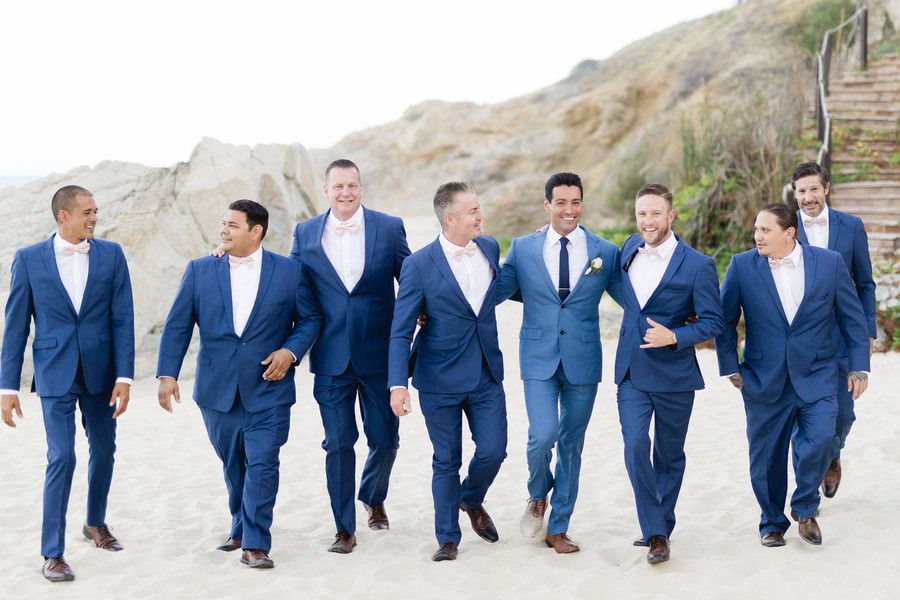 groom and groomsmen walking on beach