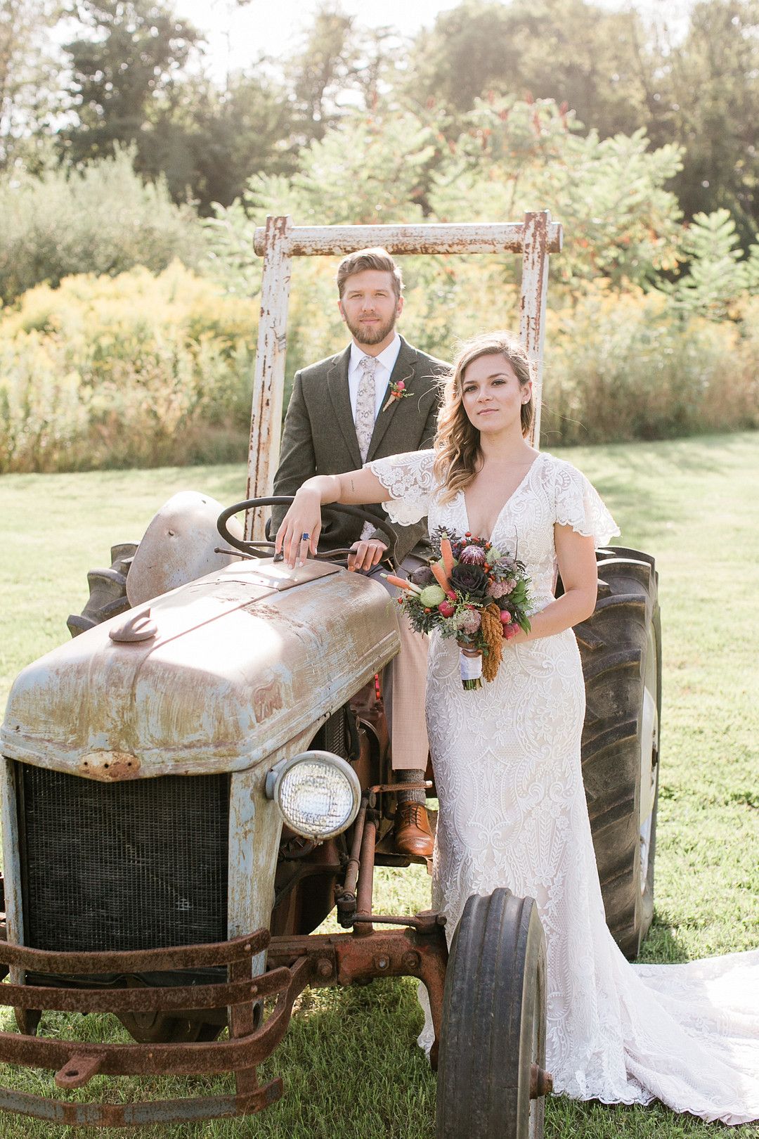bride and groom posing on a tractor