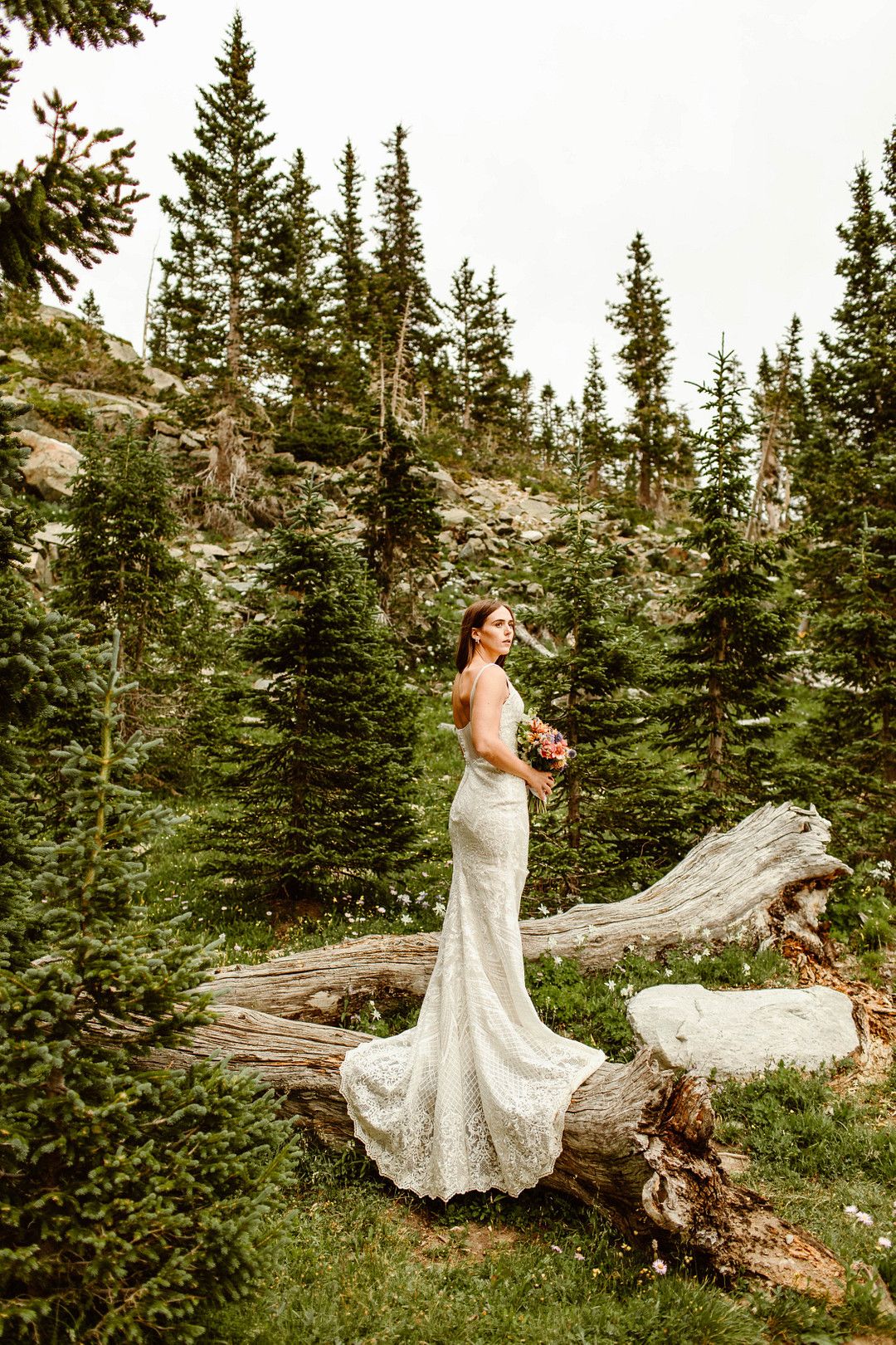 bride standing on log in wedding dress
