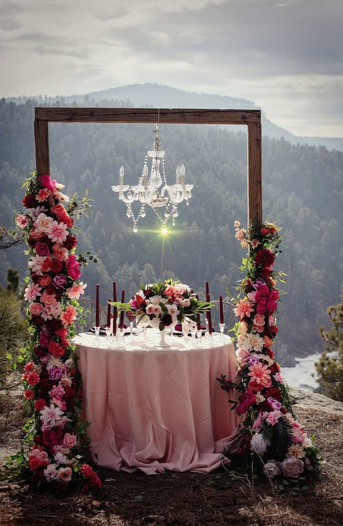 round table with hanging chandelier and large floral displays 