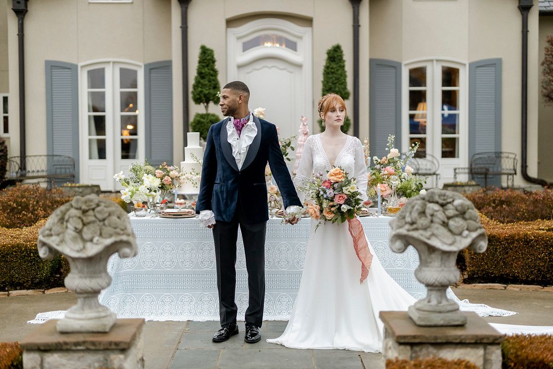 bride and groom holding hands in front of mansion