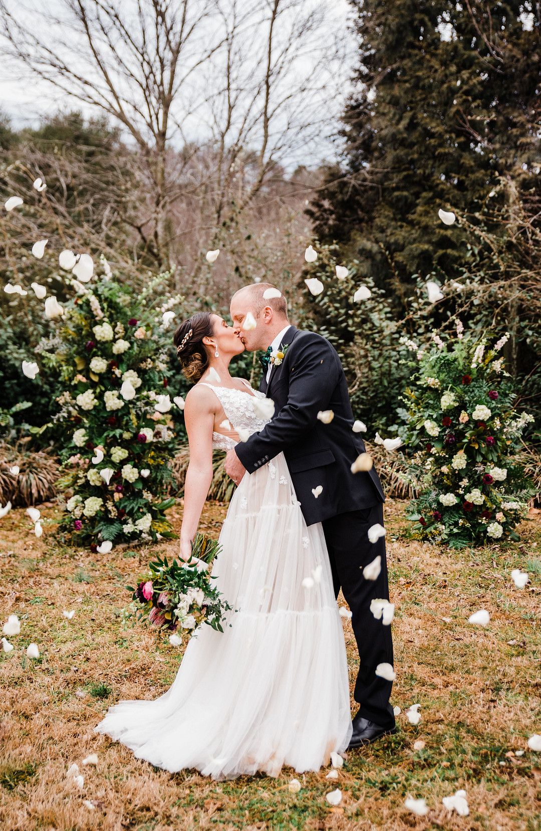 bride and groom kissing at colorful petal themed wedding styled shoot