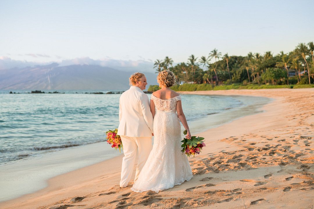 two brides walking down the beach 