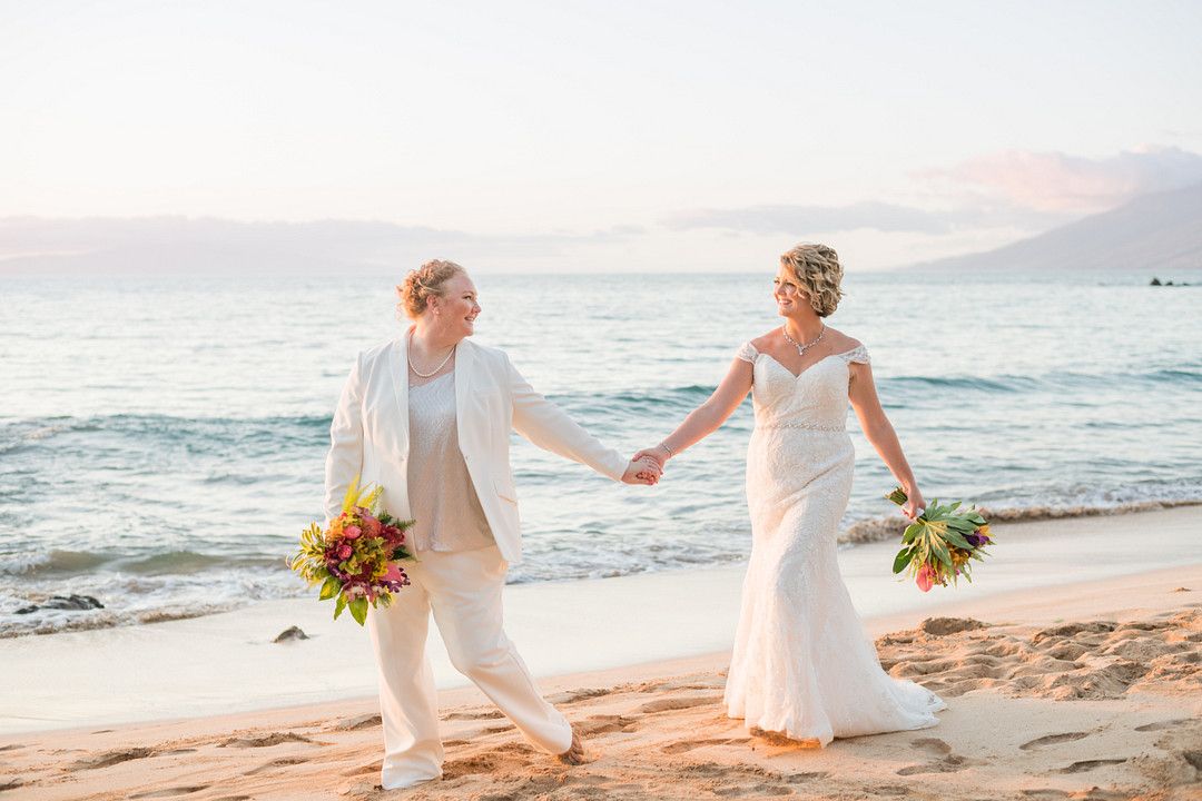 brides walking on beach celebrating