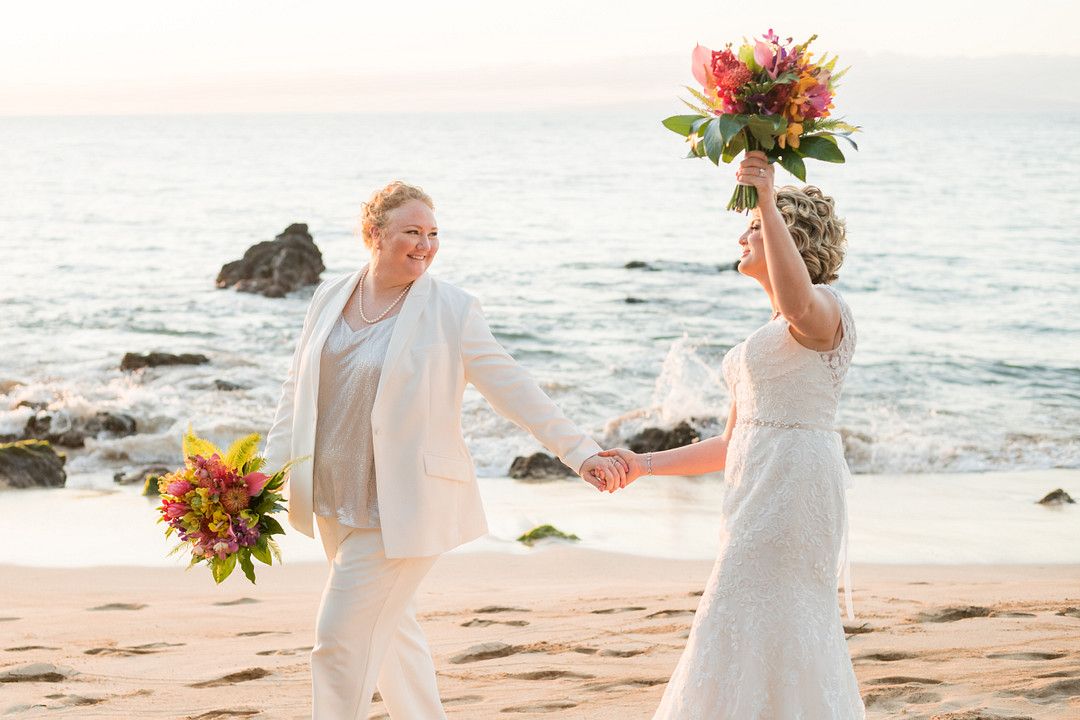 brides walking on beach celebrating