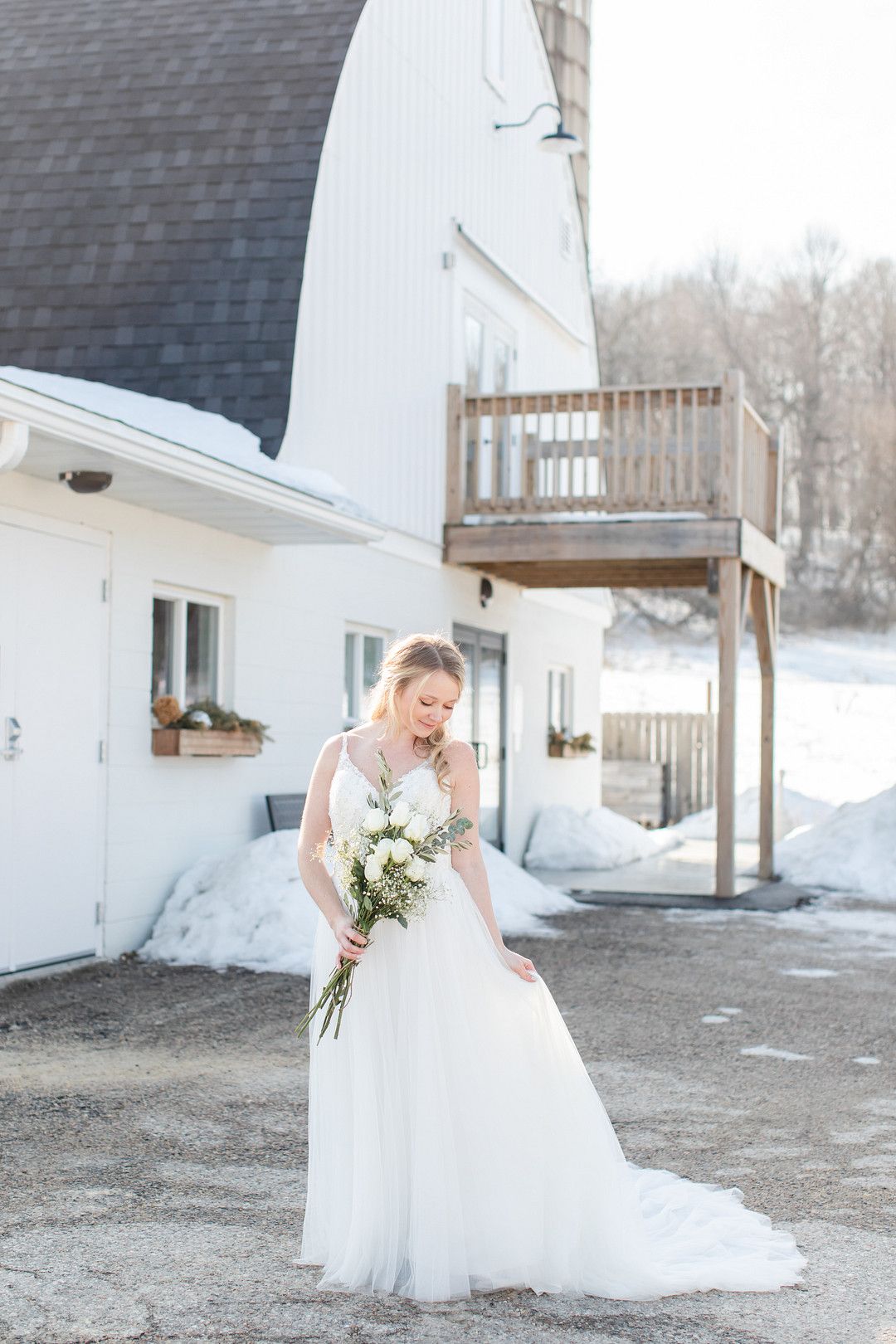 bride in wedding dress in front of barn