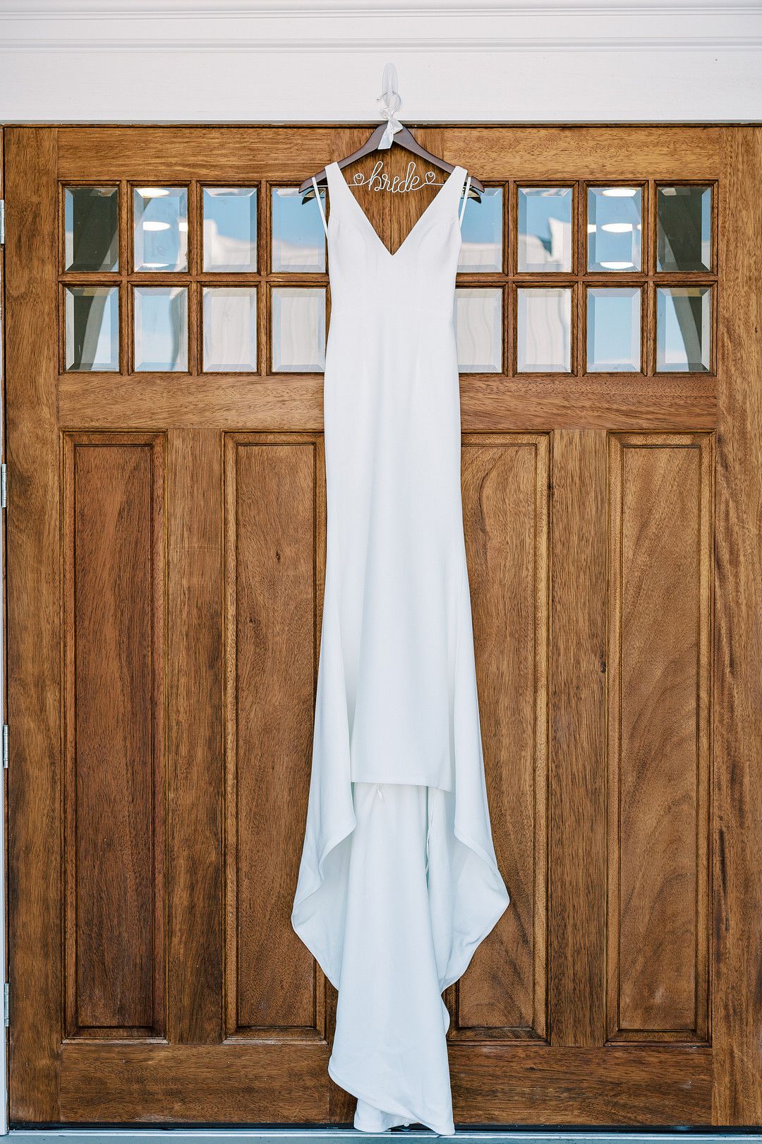 modern traditional wedding dress hanging on chapel door