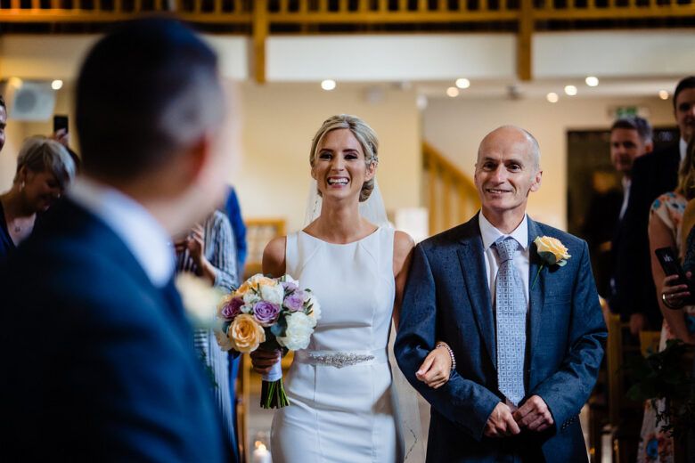 bride walking down aisle with father during wedding ceremony