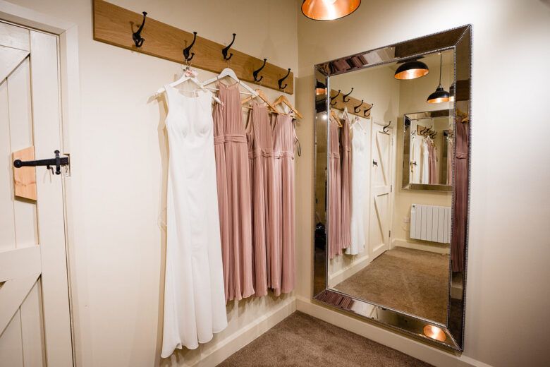 wedding and bridesmaid dresses hanging in bridal suite