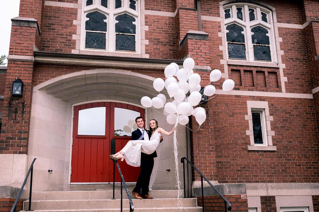 groom holding bride who has balloons in her hand