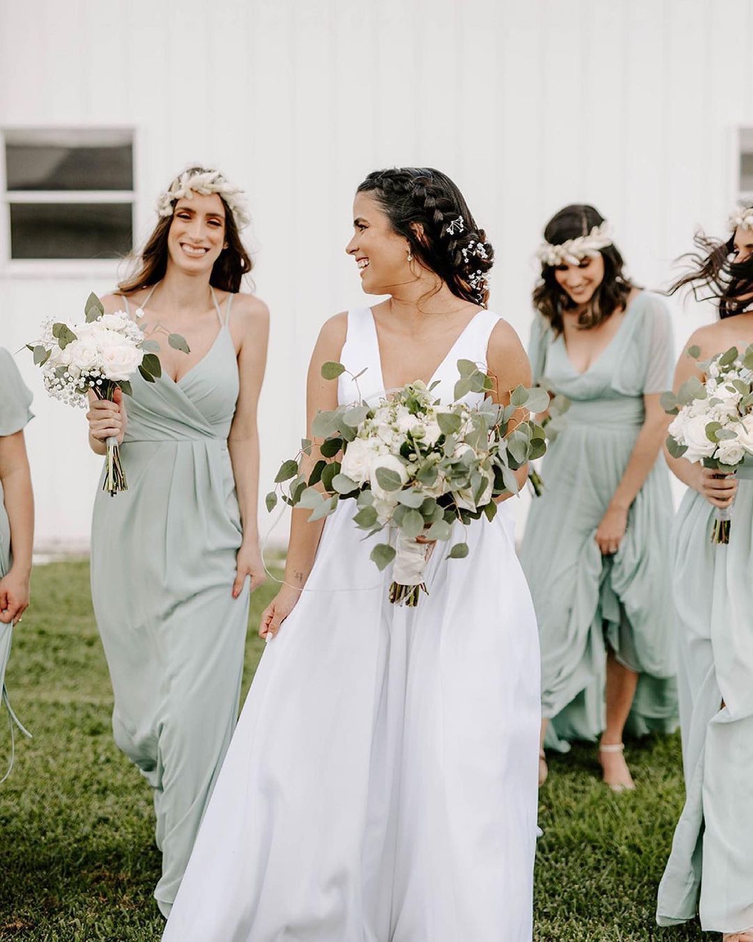 bride in wedding dress and bridesmaids in sage green dresseswalking