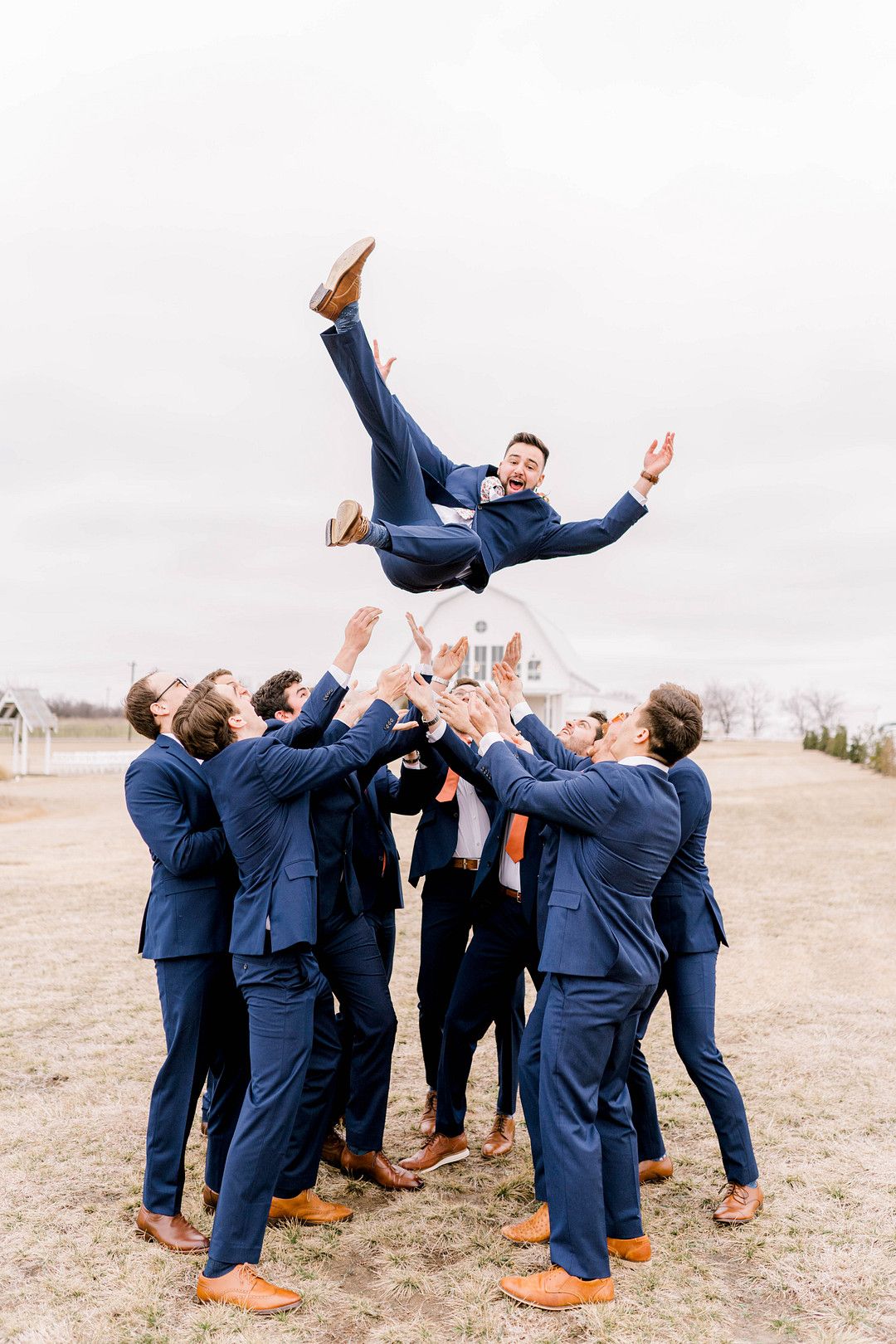 groomsmen lifting groom into the air