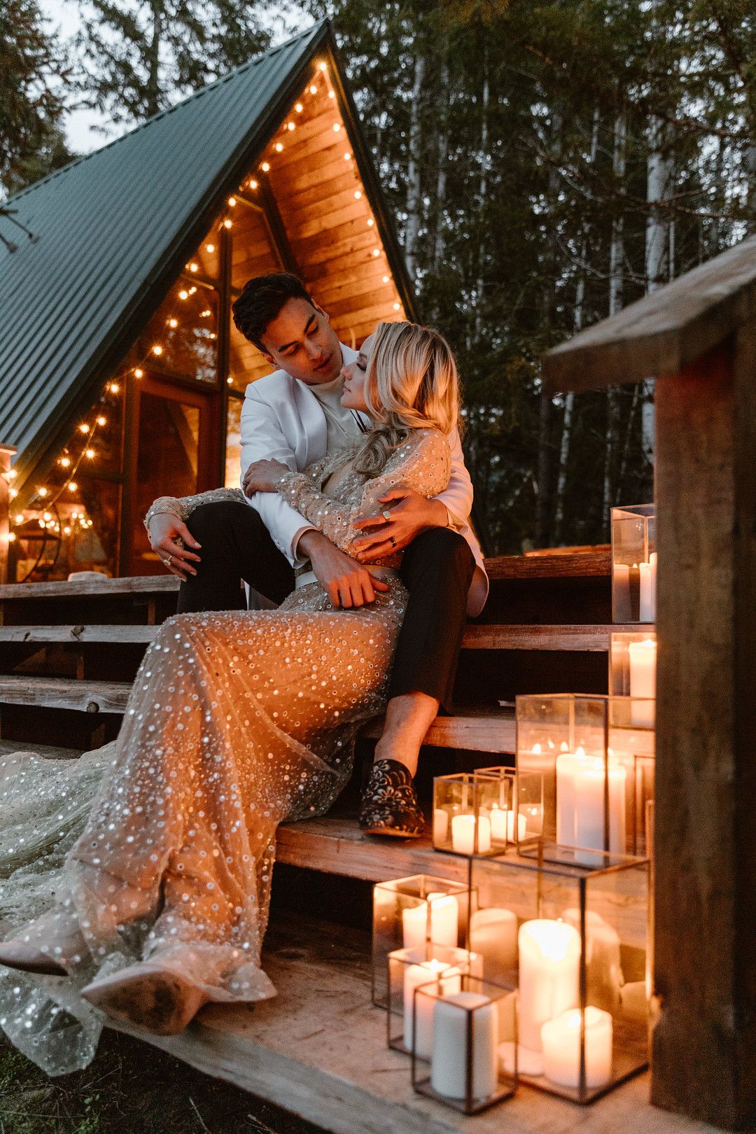 bride and groom sitting near cabin with candles