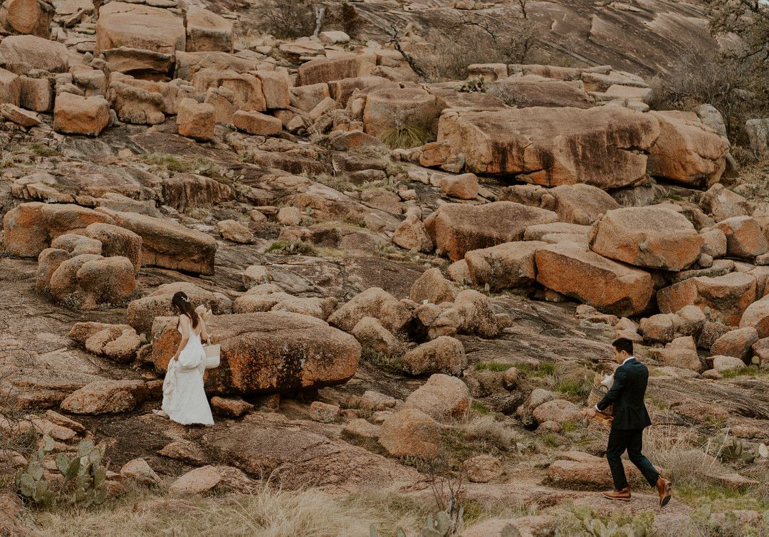 bride and groom climbing boulders