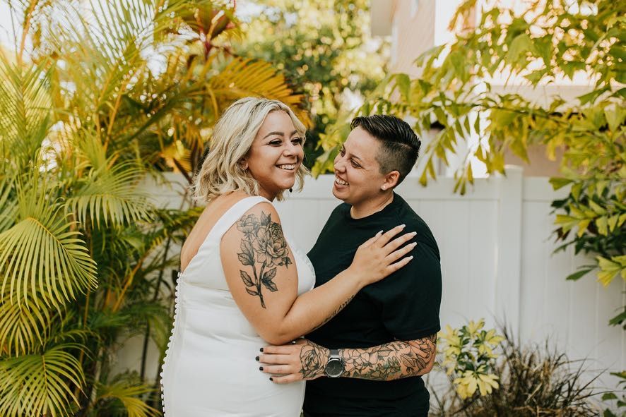 two brides embracing at intimate oceanside wedding