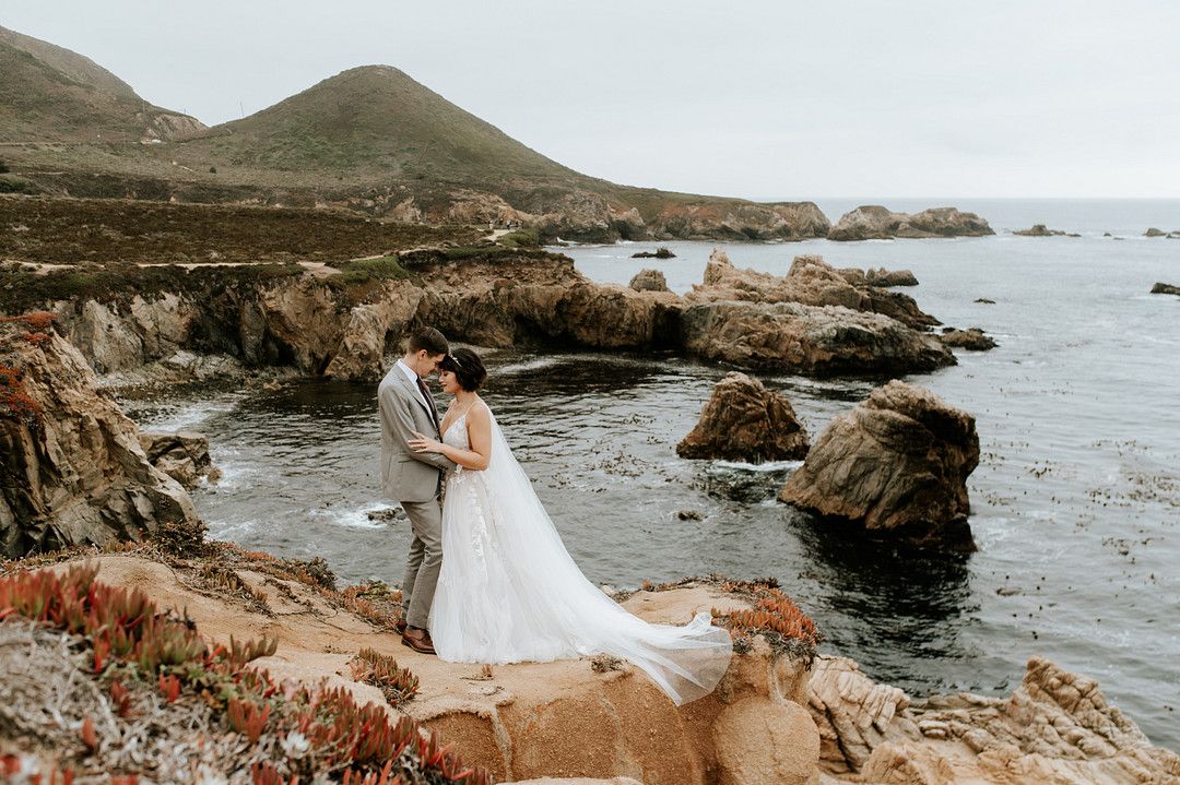 bride and groom standing on cliff in a coastal wedding in Big Sur, California