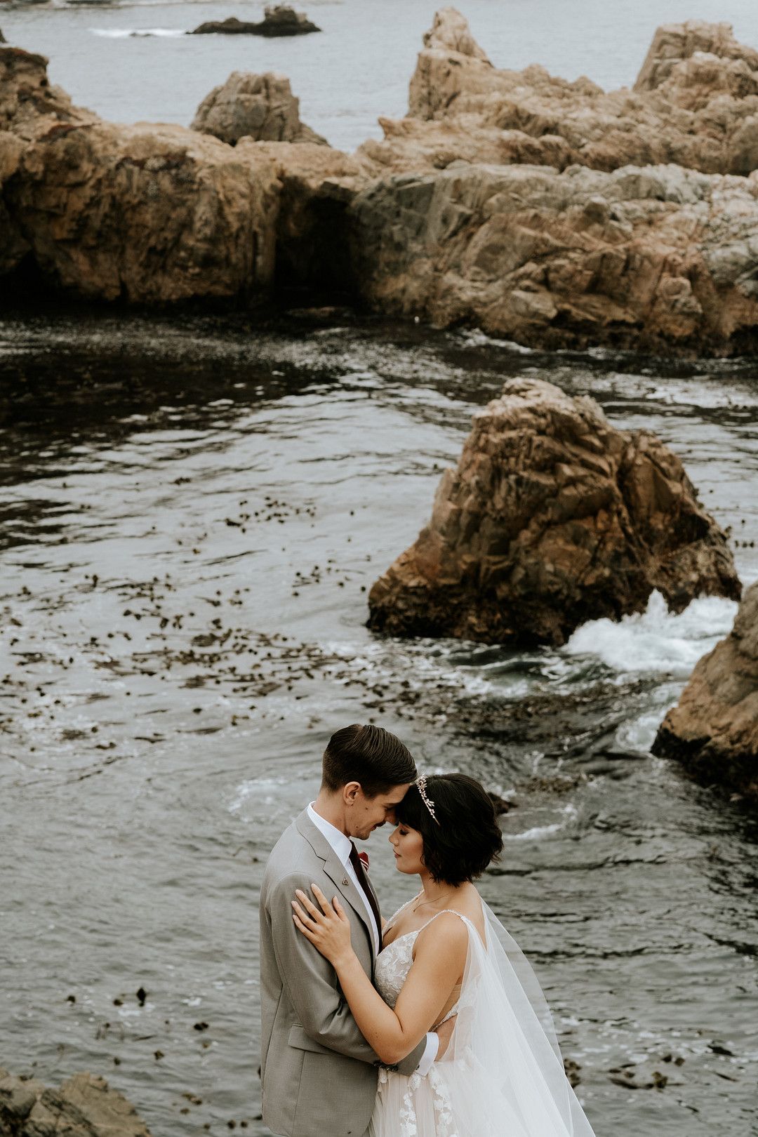 Bride and groom standing on cliff in a coastal wedding in Big Sur, California