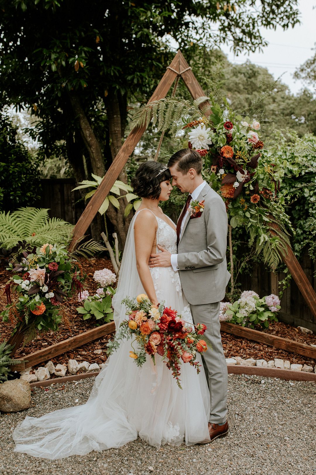 Bride and groom hugging in front of vibrant floral backdrop