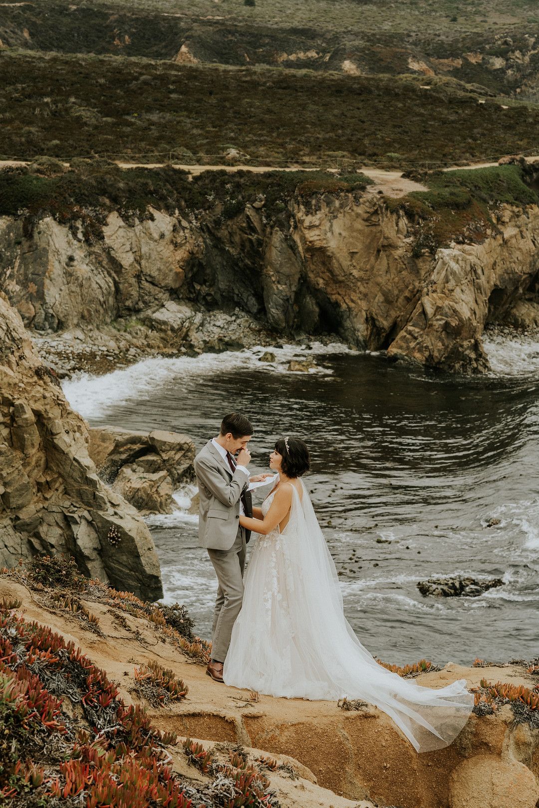 Bride and groom reading vows with coastal backdrop