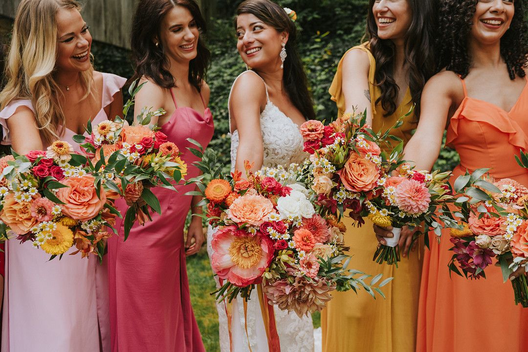 Bride and bridesmaids holding vibrant wedding floral bouquets 