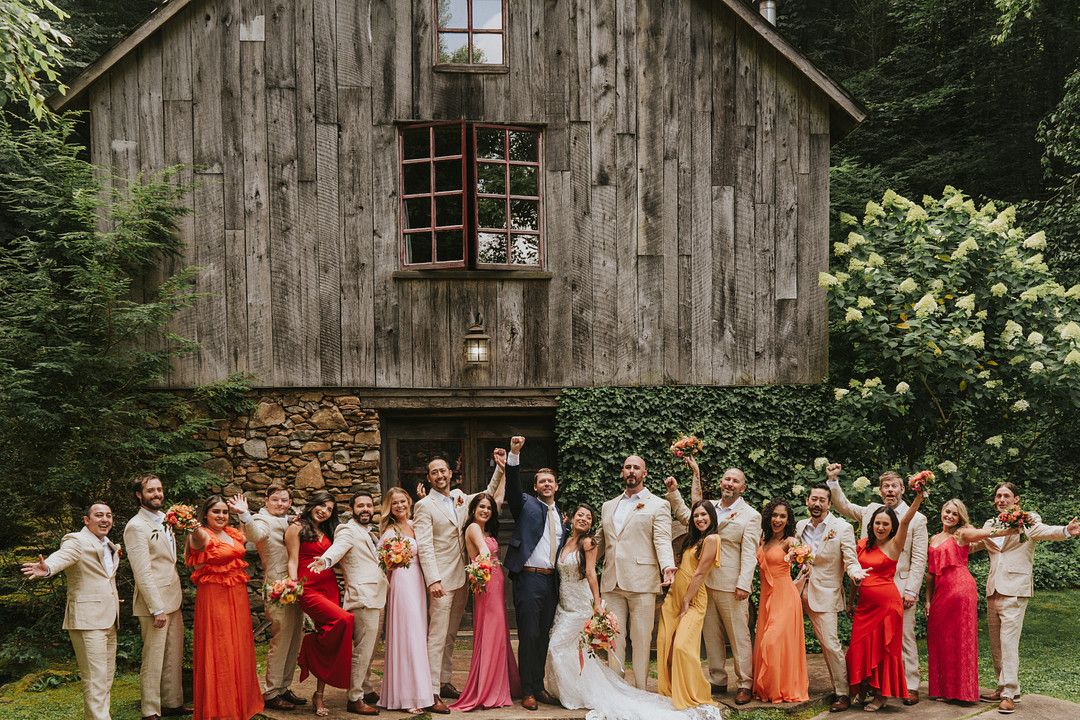 Full wedding party posing in front of barn at boho wedding in North Carolina
