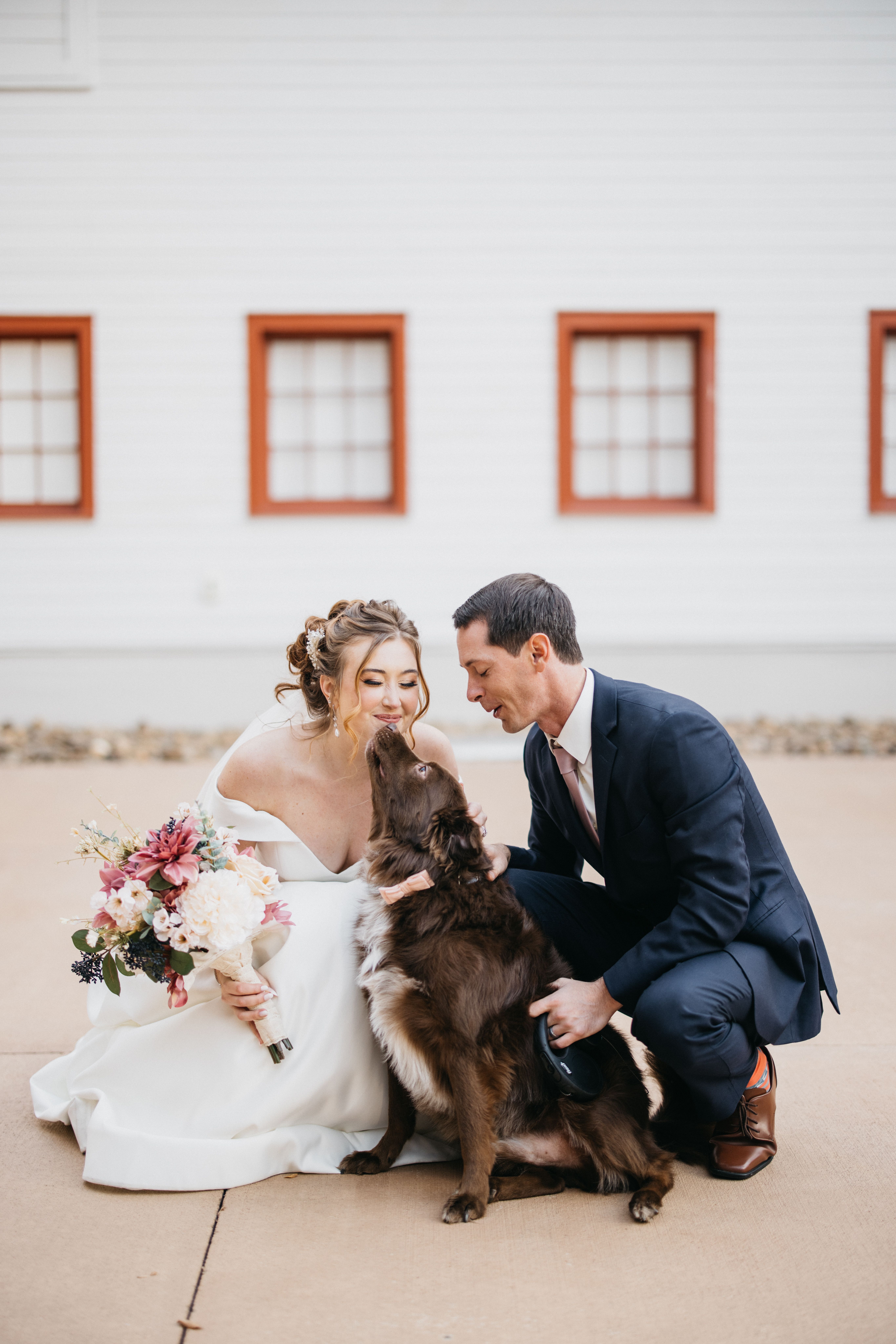 bride and groom posing for a photo with a dog