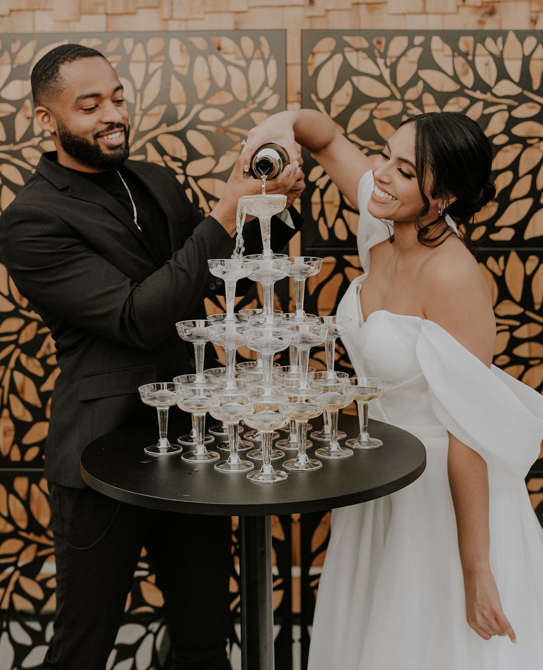 bride and groom pouring champagne tower at elegant barn wedding in florida