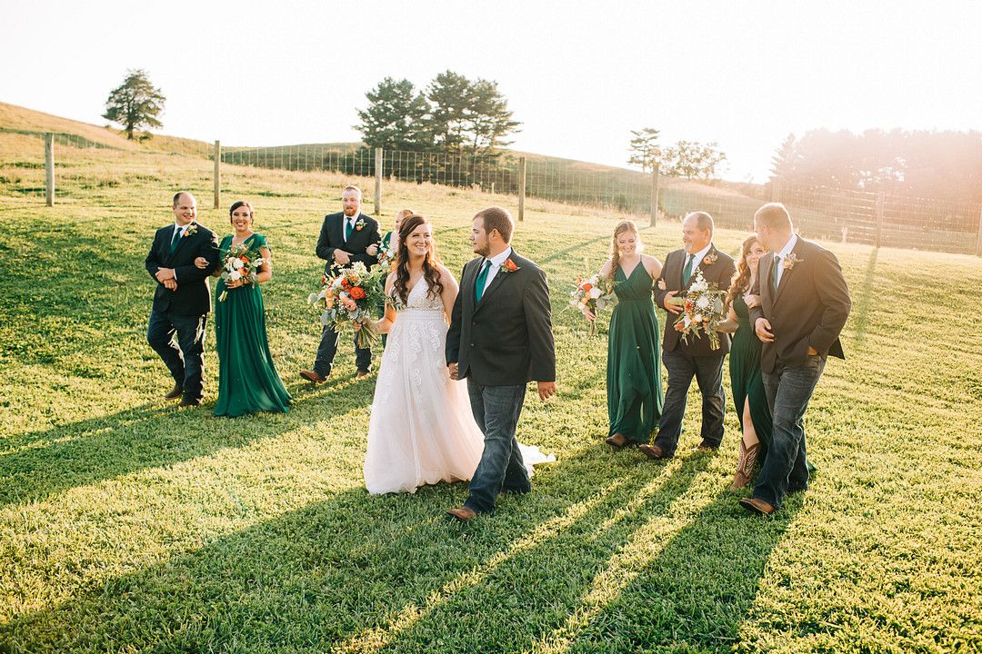 people walking through field at rustic barn wedding