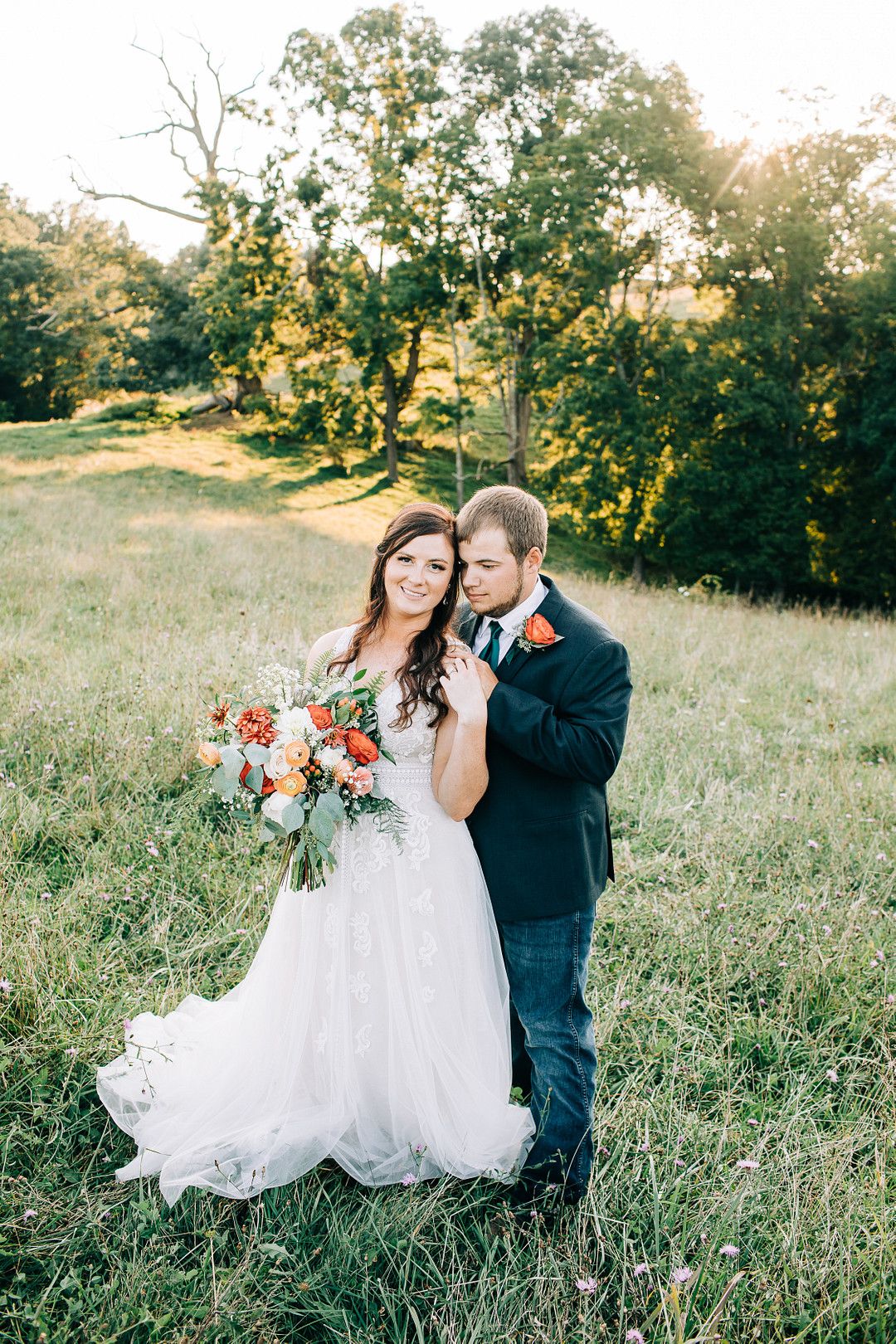 couple standing in field at rustic barn wedding
